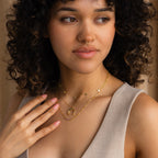 A woman with curly hair wears the Lace Birthstone Necklace and a nose ring, gently touching her chest while looking to the side.