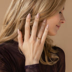 A smiling woman with long blonde hair shows her manicured hand wearing the Chevron Birthstone Rings Set, looking to the side.