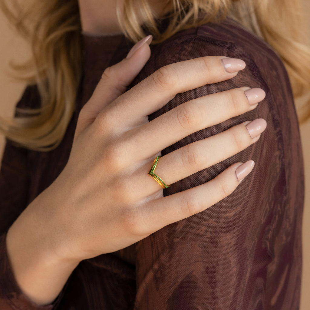 A nude-nailed hand rests on a shoulder, highlighting a gold chevron ring on the ring finger, just like the Chevron Birthstone Rings Set.