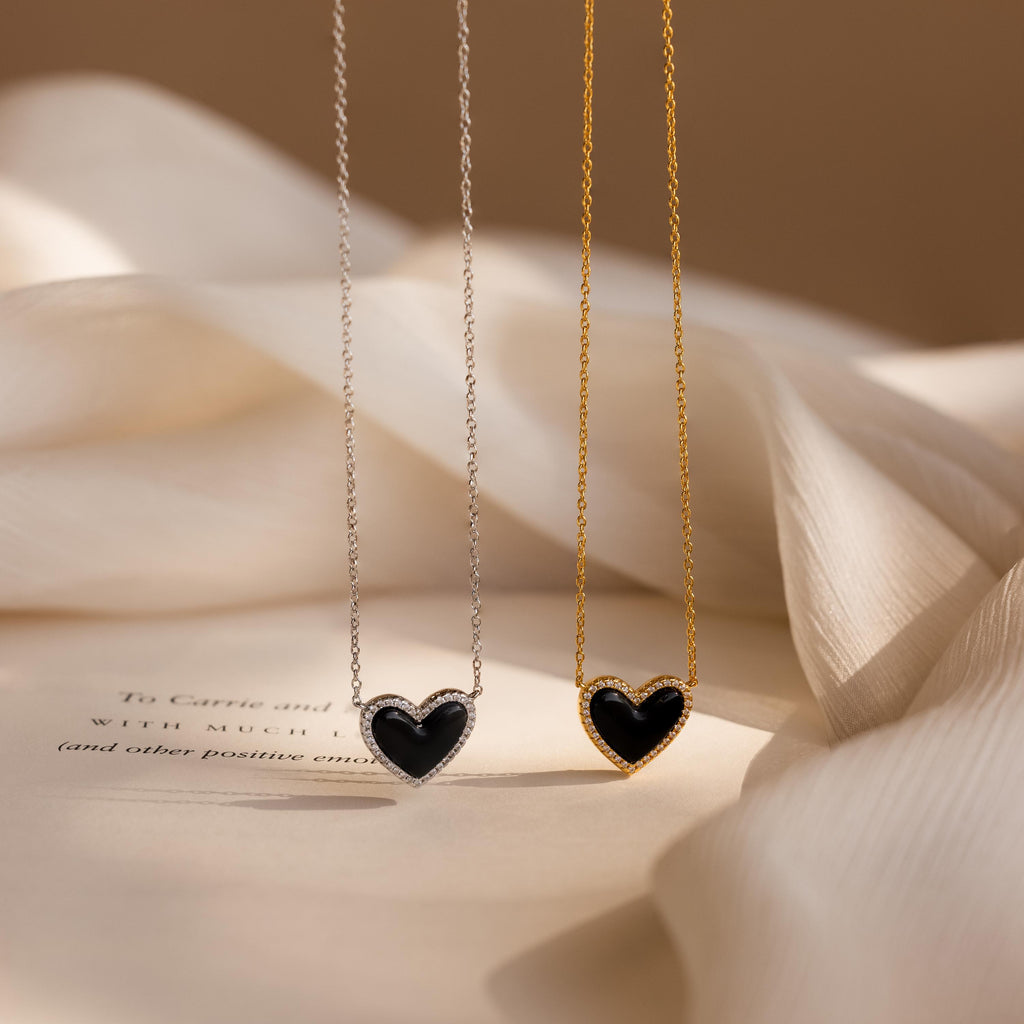 The Pave Onyx Puff Heart Necklace rests on a delicate chain against a soft beige background, adding the perfect touch of coquette style.