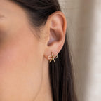 Close-up of a woman's ear wearing Classic Ribbon Bow Huggies in gold, adding a subtle, feminine touch to her look.