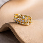 Gold Art Deco diamond ring set featuring various cut stones in stacked bands, displayed on a sculpted beige surface.