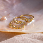 Three gold Art Deco rings with various diamond cuts displayed on a pearlescent shell surface.