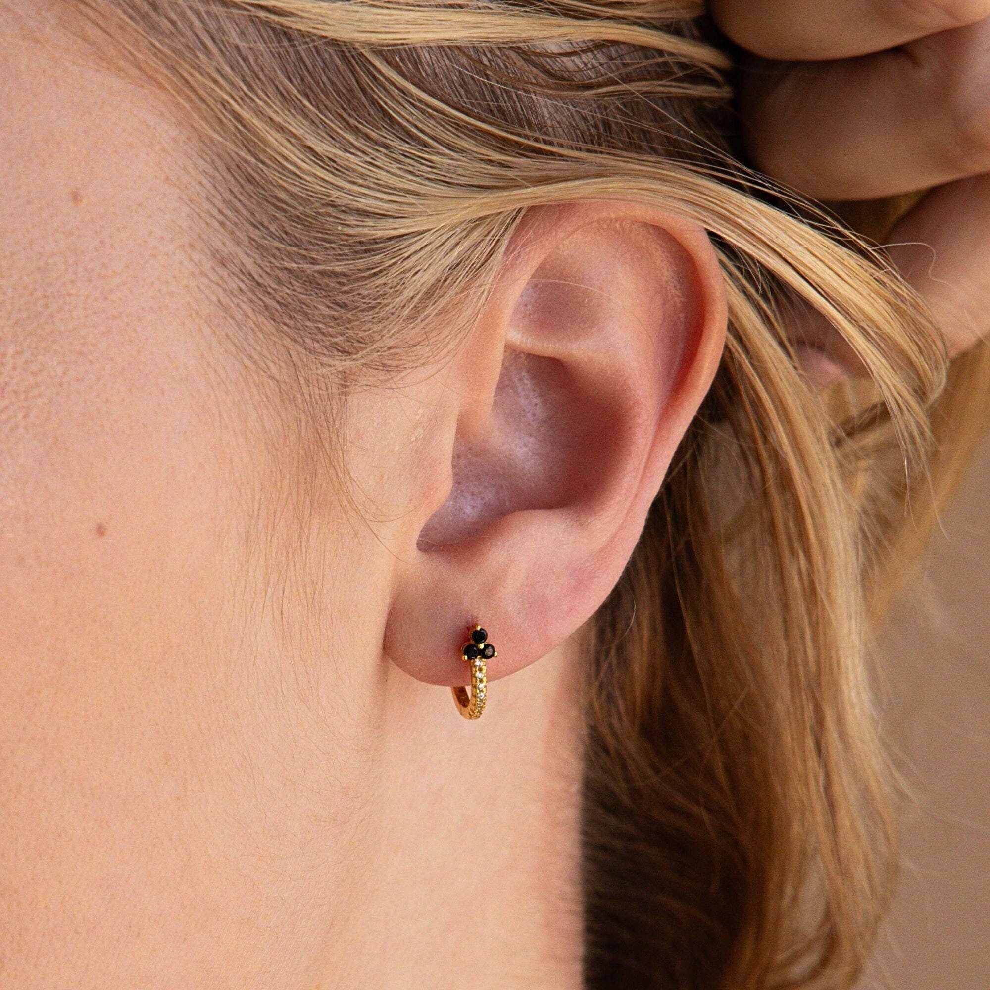 Close-up of a woman’s ear wearing Onyx Lily Huggies—delicate gold hoops accented with elegant black onyx beads.