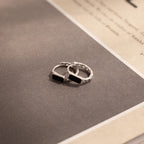 A pair of rings on a book, their design reminiscent of the elegant Onyx Link Huggies.