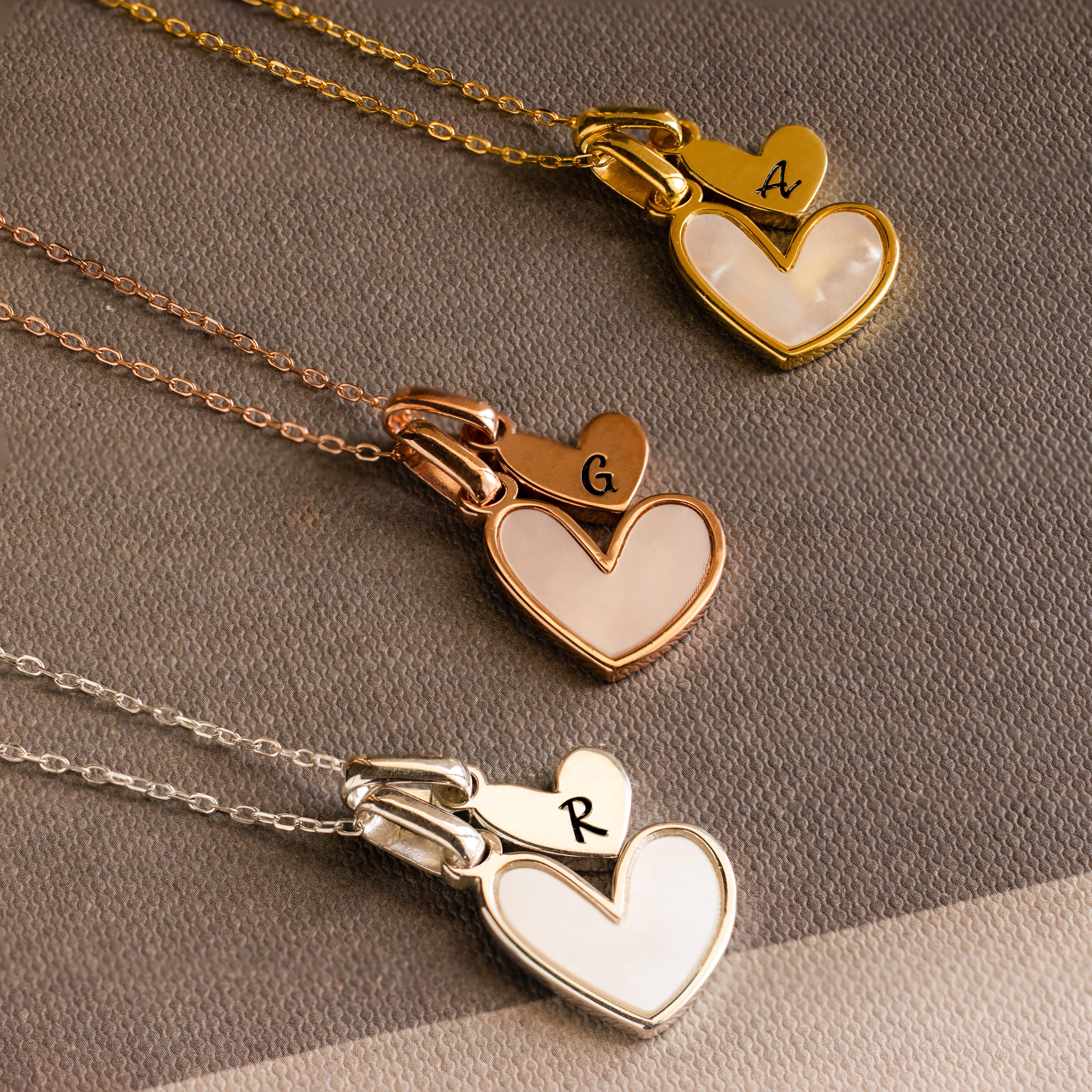 The Stylish Pearl Initial Heart Necklace features three heart-shaped charms in gold, rose gold, and silver, each personalized with initials A, G, and R. A perfect way to express your style or give as a thoughtful gift.