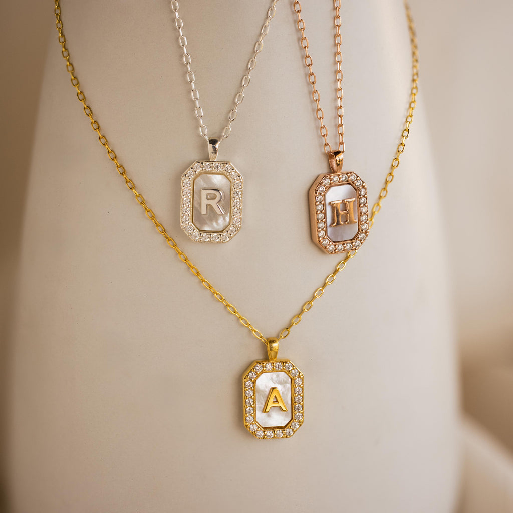 Three Pave Pearl Initial Necklaces, each with a gold or silver rectangular pendant featuring the letters R, H, and A, make a stunning CZ diamond necklace set.