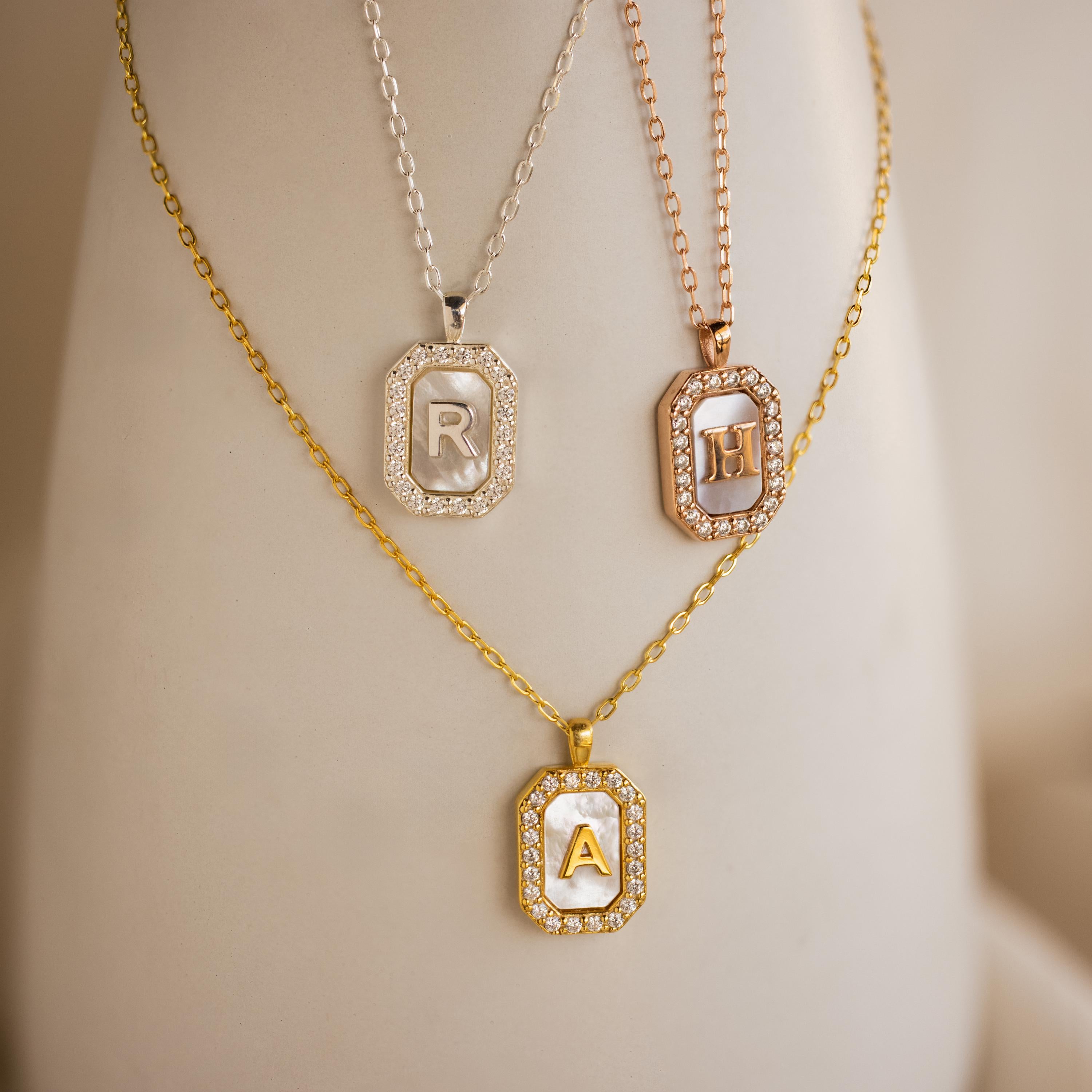 Three Pave Pearl Initial Necklaces, each with a gold or silver rectangular pendant featuring the letters R, H, and A, make a stunning CZ diamond necklace set.
