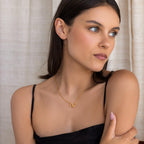 Woman in a black spaghetti strap top wears the elegant Interlocking Pave Charm Necklace, looking to the side against a neutral background.