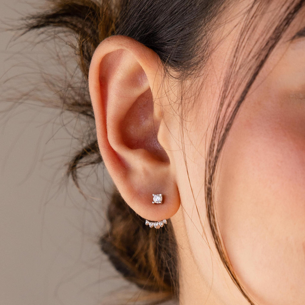 Close-up of a woman's ear with two earrings—a square stud and a small hoop with stones—paired with Round Diamond Ear Jackets in Sterling Silver for a touch of modern elegance.