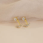 Round Diamond Ear Jackets in 18K Gold are displayed on a beige textured fabric background, highlighting the refined elegance and sparkle of these stylish earrings.