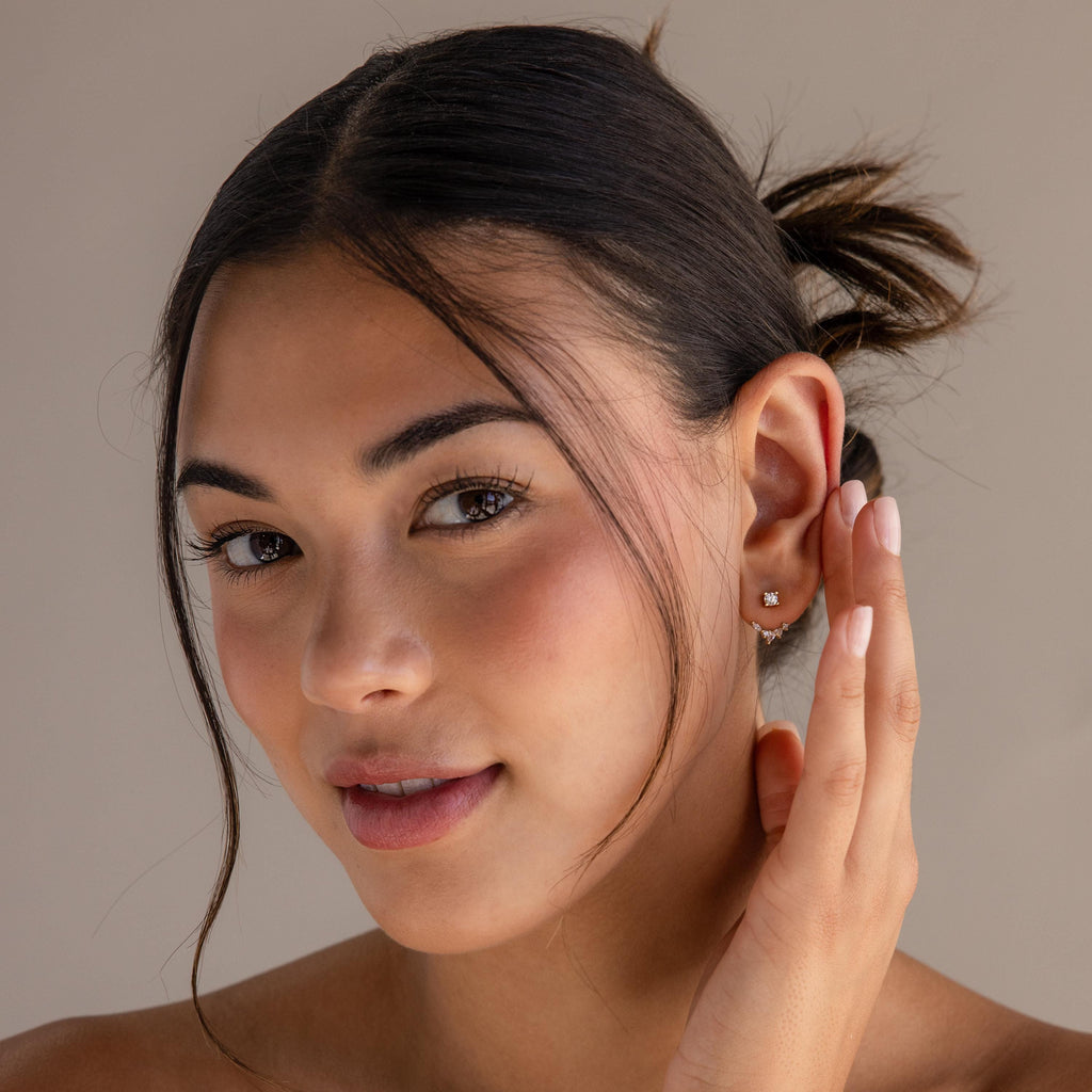 Woman with dark hair in a bun smiles softly at the camera, showing off Diamond Cluster Ear Jackets with a stylish front-back design.