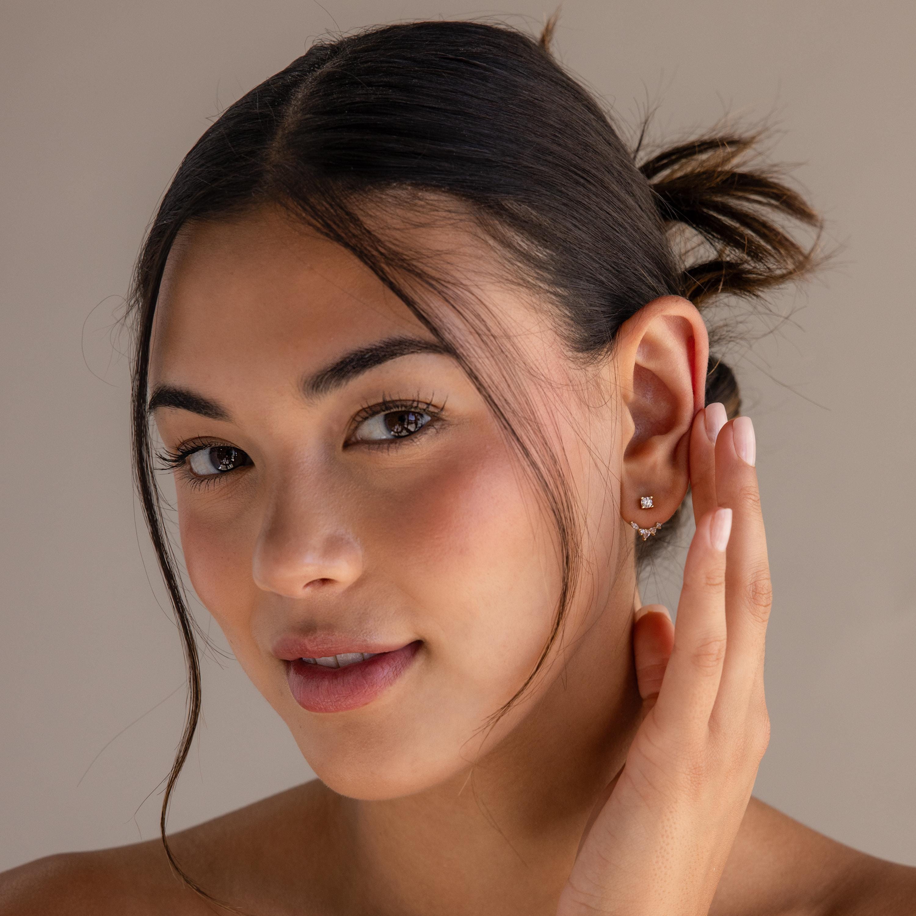Woman with dark hair in a bun smiles softly at the camera, showing off Diamond Cluster Ear Jackets with a stylish front-back design.