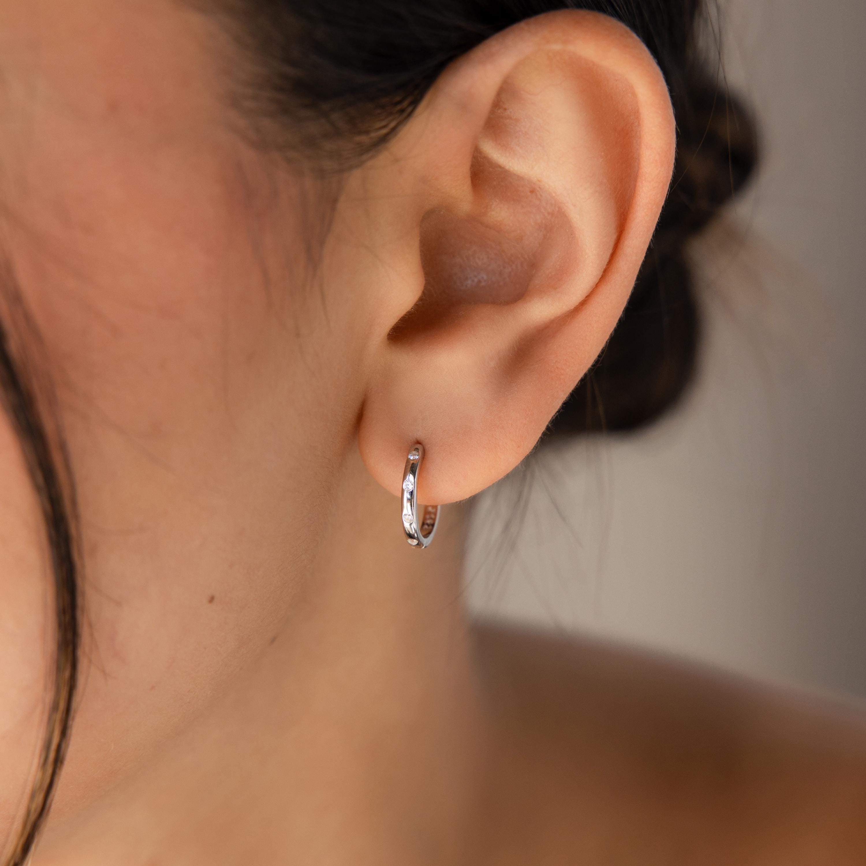 Close-up of a woman's ear with Classic Diamond Sprinkle Huggies, featuring a timeless silver design that adds a touch of sparkle.