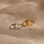 Two pairs of Classic Diamond Sprinkle Huggies, in silver and gold, are displayed on a beige fabric background.