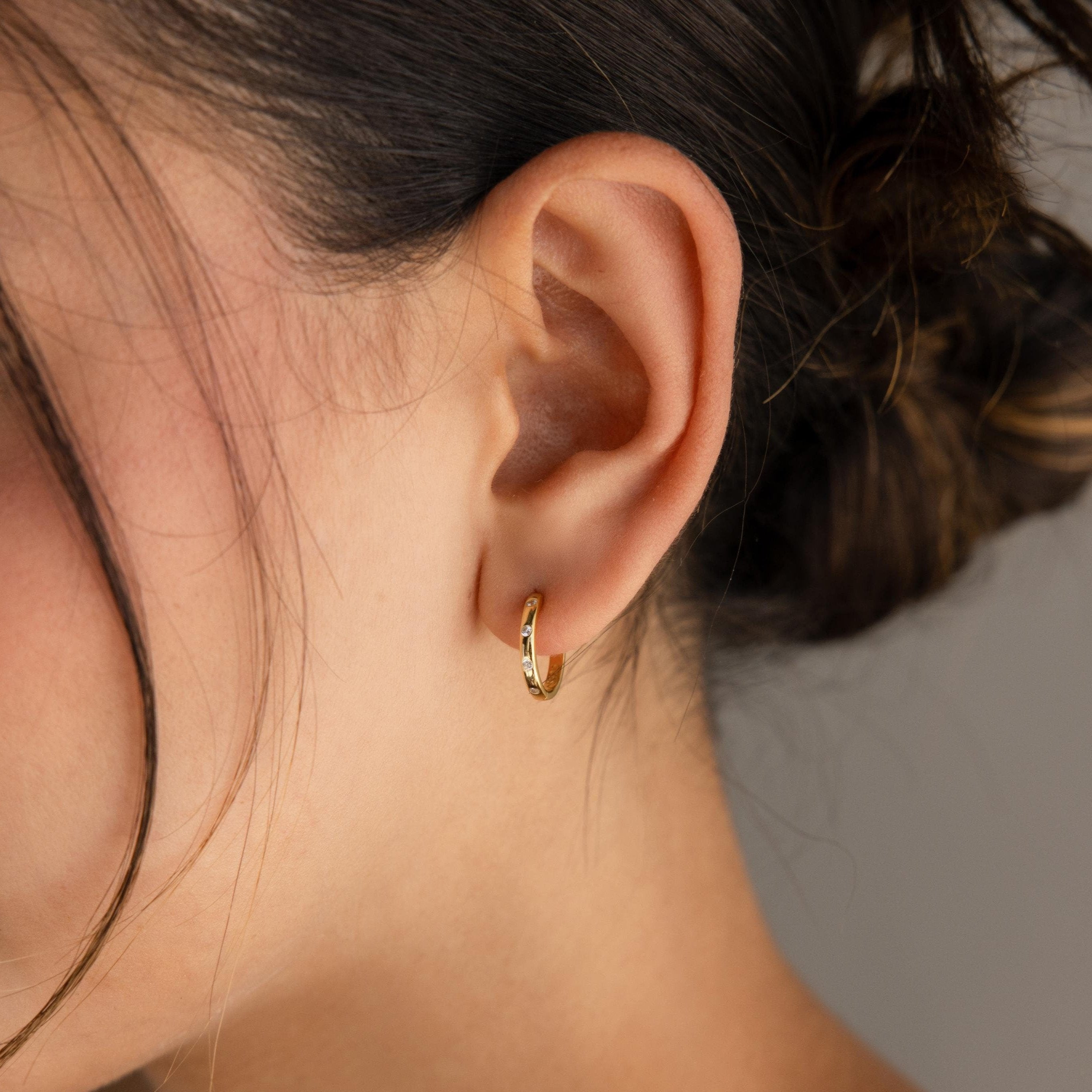 A close-up of a woman's ear adorned with Classic Diamond Sprinkle Huggies.