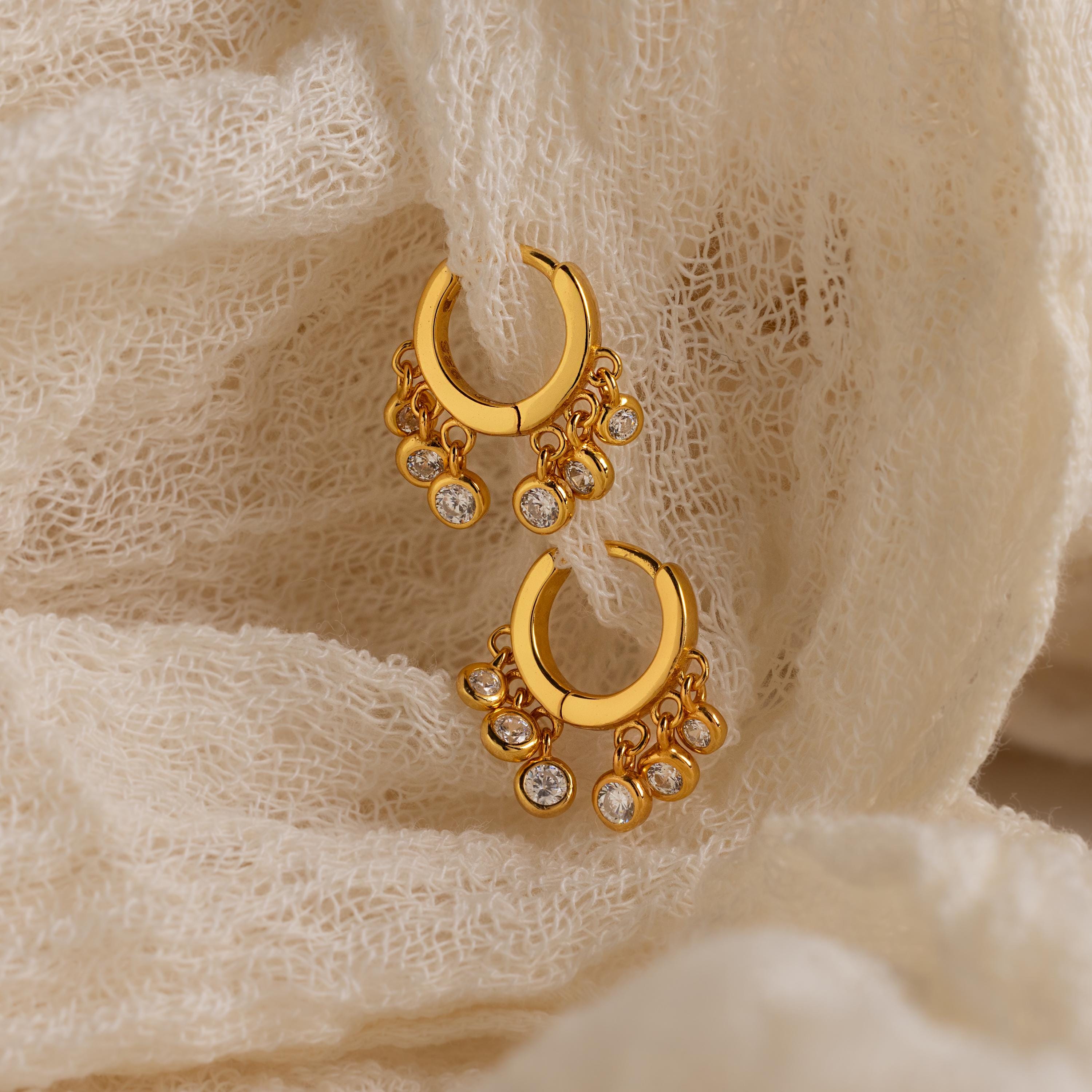 Chandelier Diamond Huggies showcased on textured cream-colored fabric.