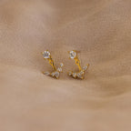 Diamond Cluster Ear Jackets featuring a delicate floral design, with gold and diamond studs, displayed on a beige fabric background.