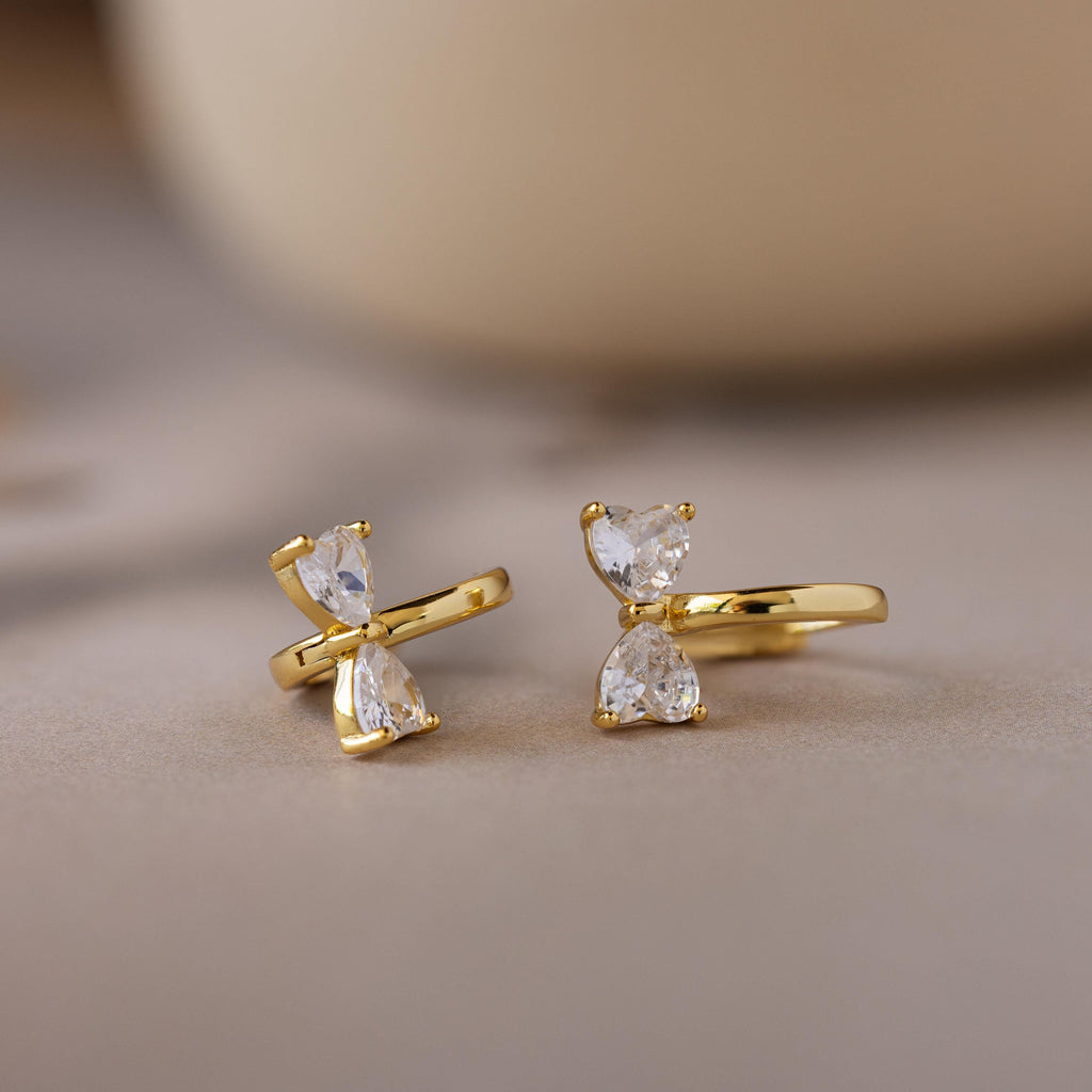 Diamond Bow Huggies featuring two clear, teardrop-shaped gems stacked vertically, displayed on a soft, neutral background.