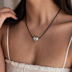 Woman wearing a white ruched top accessorized with the Chunky Puff Heart Necklace, featuring a black cord and a silver puff heart pendant.