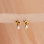 Love Knot Pearl Earrings featuring elegant pearl drops, beautifully displayed on soft beige fabric—a classic accessory for weddings.