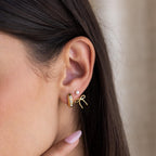 Close-up of an ear wearing three gold earrings: a hoop, a small stud, and Pearl & Bow Ear Jackets in 18K Gold.