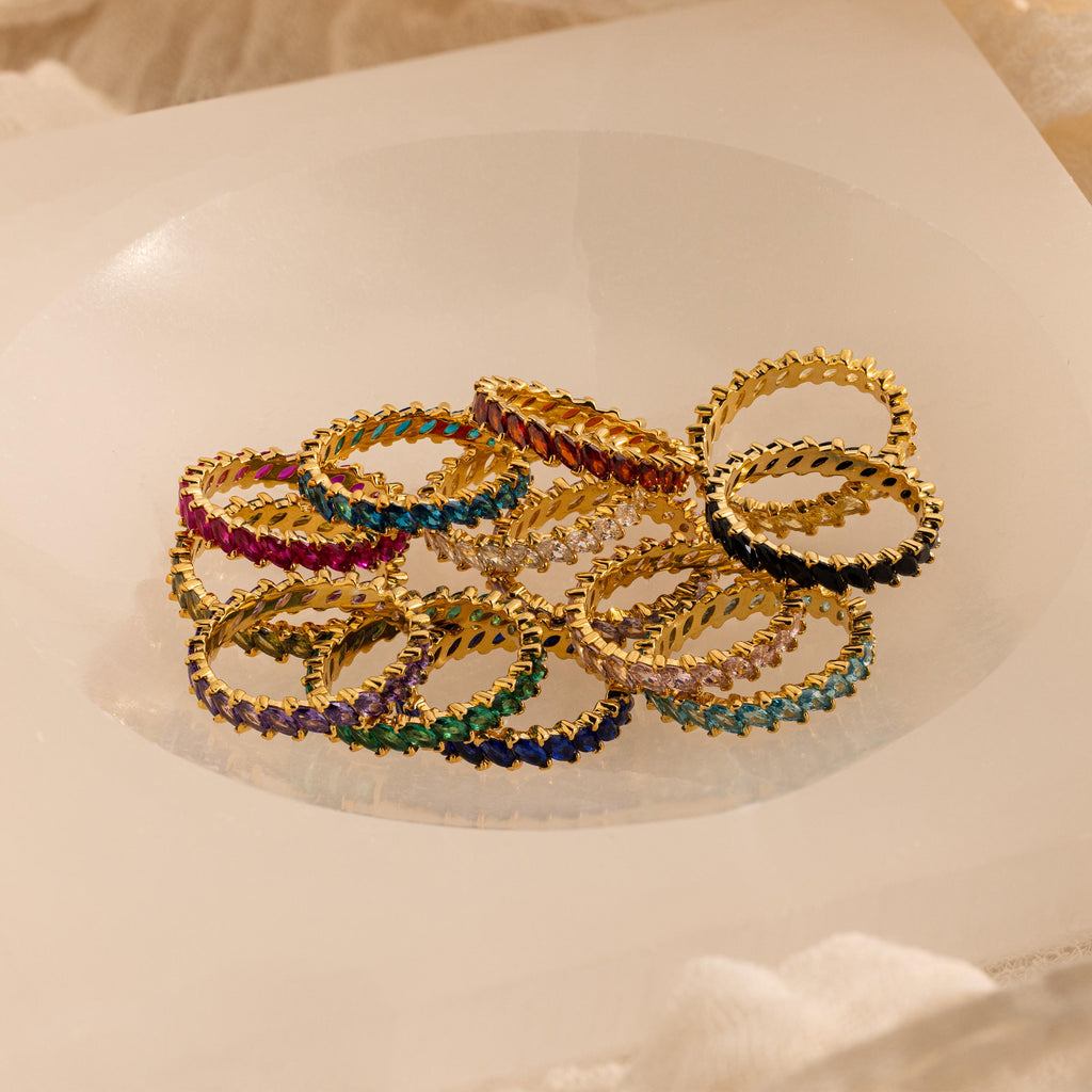 Eternity Marquise Birthstone Rings with colorful gemstones arranged in a circle on a white, translucent surface—each customizable for any birthstone, making it a thoughtful Christmas gift.