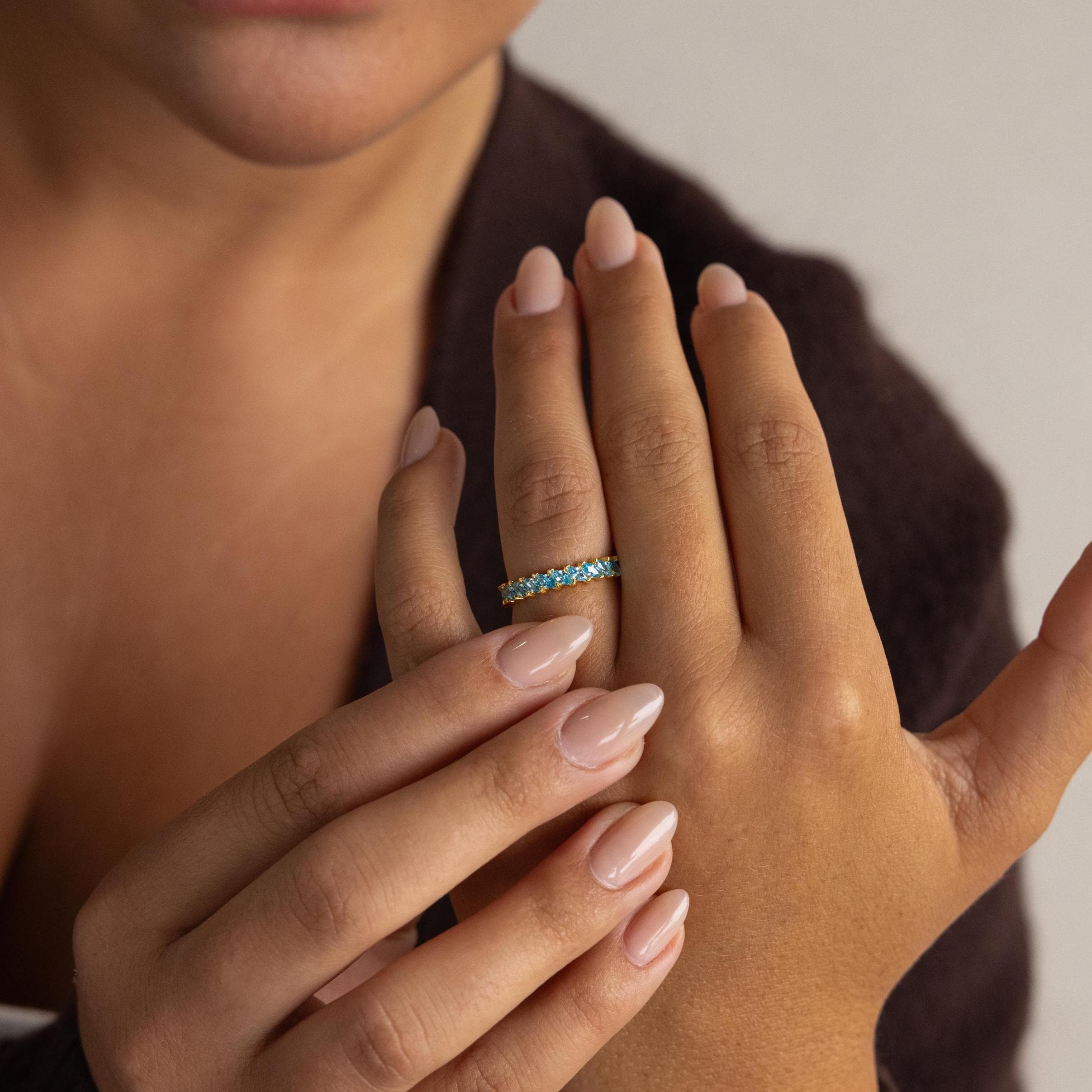 A person with nude manicured nails wears the Eternity Marquise Birthstone Ring, customized with a turquoise gemstone on their ring finger—an elegant accessory and a perfect Christmas gift.