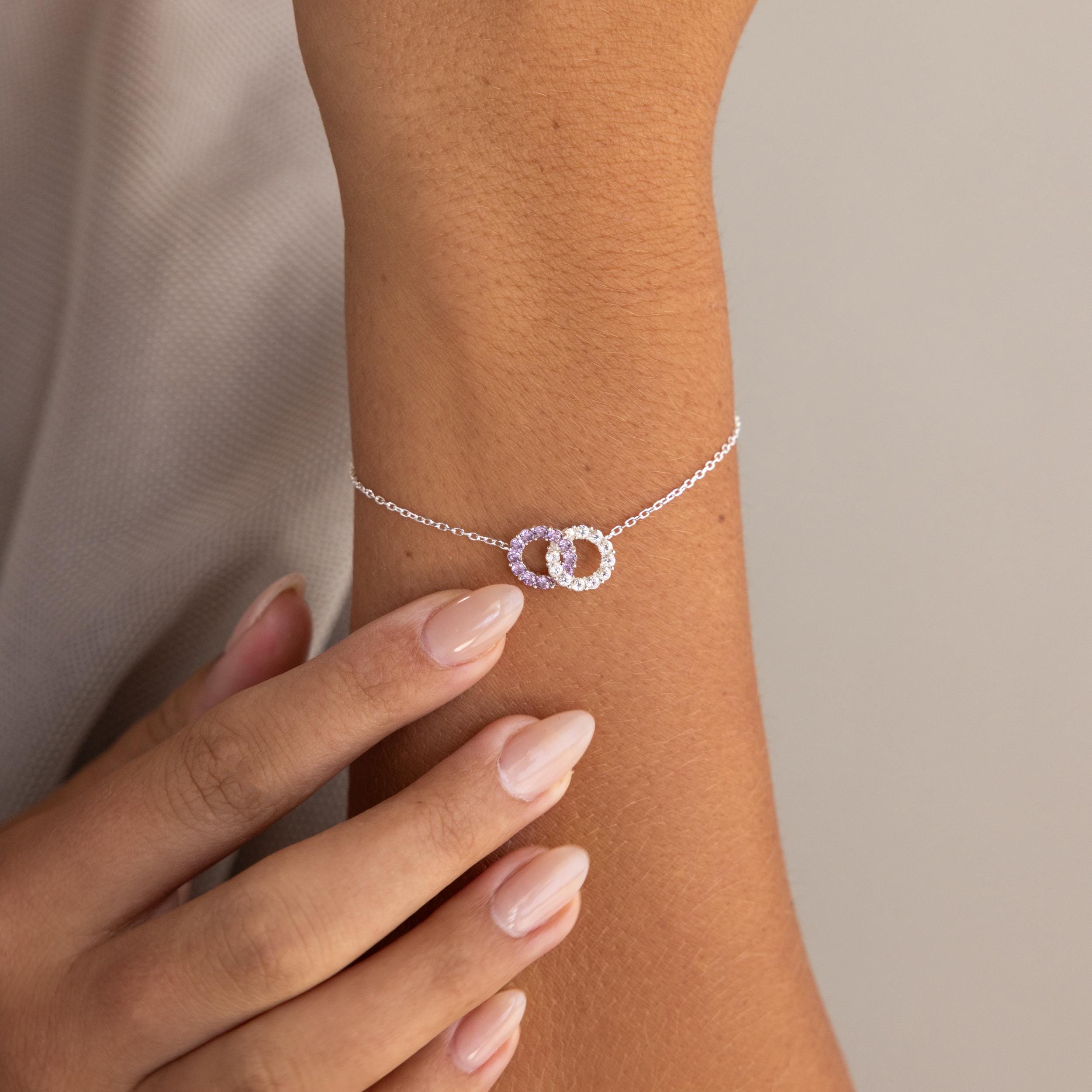 The Interlocking Duo Birthstone Bracelet features two circles and customizable gemstones, making it a meaningful and elegant gift for any occasion.