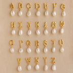 Initial Pearl Drop Studs featuring gold letter charms with dangling pearls, beautifully arranged on a beige background—ideal for creating personalized initial earrings or custom stud earrings.