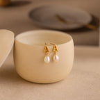 A pair of Initial Pearl Drop Studs in a container.