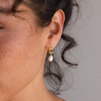 A close-up of a woman's ear adorned with elegant Initial Pearl Drop Studs.