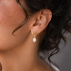 Close-up of a woman wearing Initial Pearl Drop Studs—gold B initial earrings with a dangling white pearl, perfect for fans of personalized jewelry.