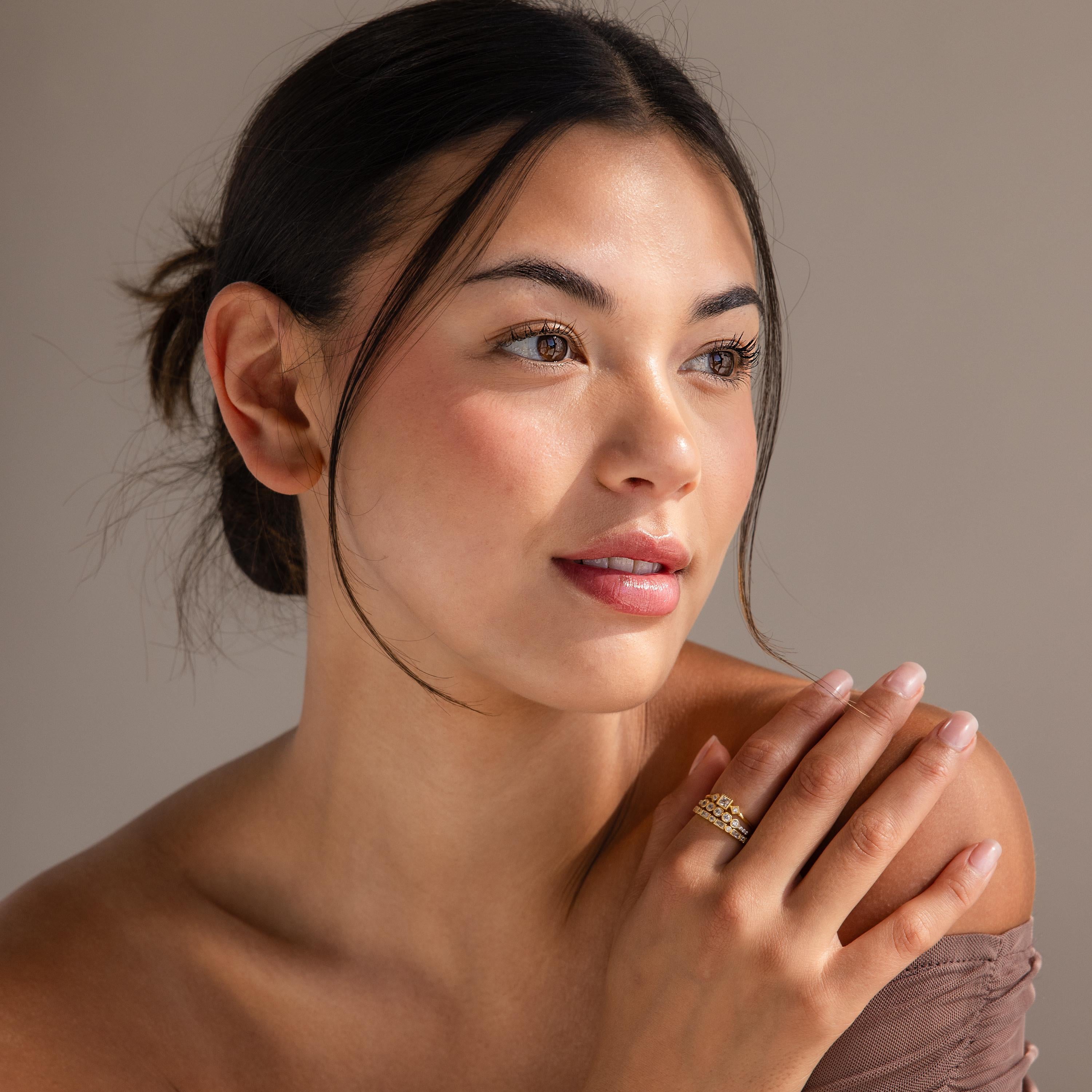 Model wearing a gold Art Deco diamond ring set, gently resting her hand on her shoulder, with a soft smile and natural lighting.