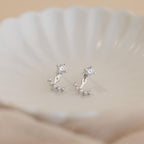 Round Diamond Ear Jackets in Sterling Silver, featuring arc design gemstone accents, reminiscent of elegant diamond stud earrings, displayed on a white shell-shaped dish.