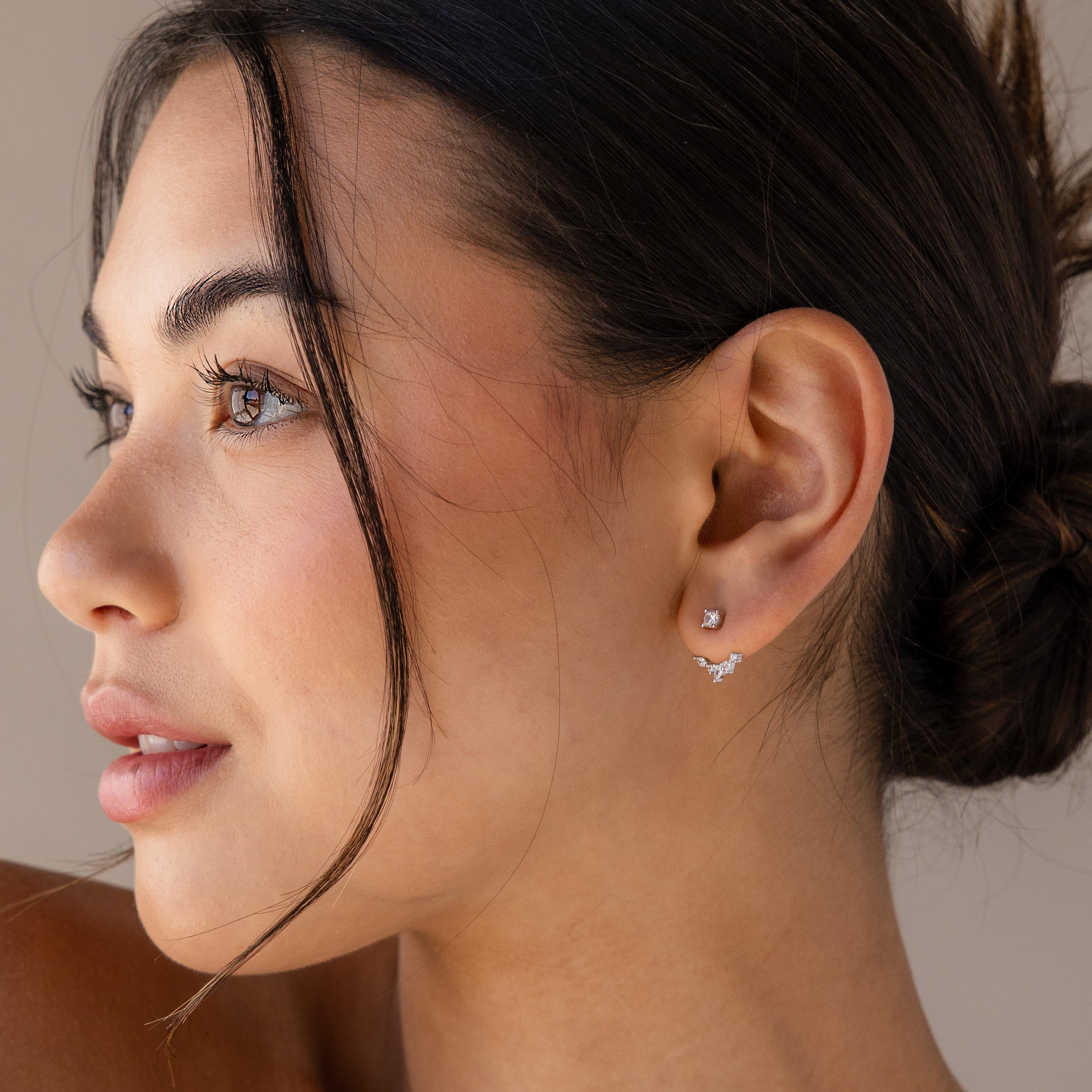 A woman with brown hair in a low bun wears Diamond Cluster Ear Jackets and gazes to the left.