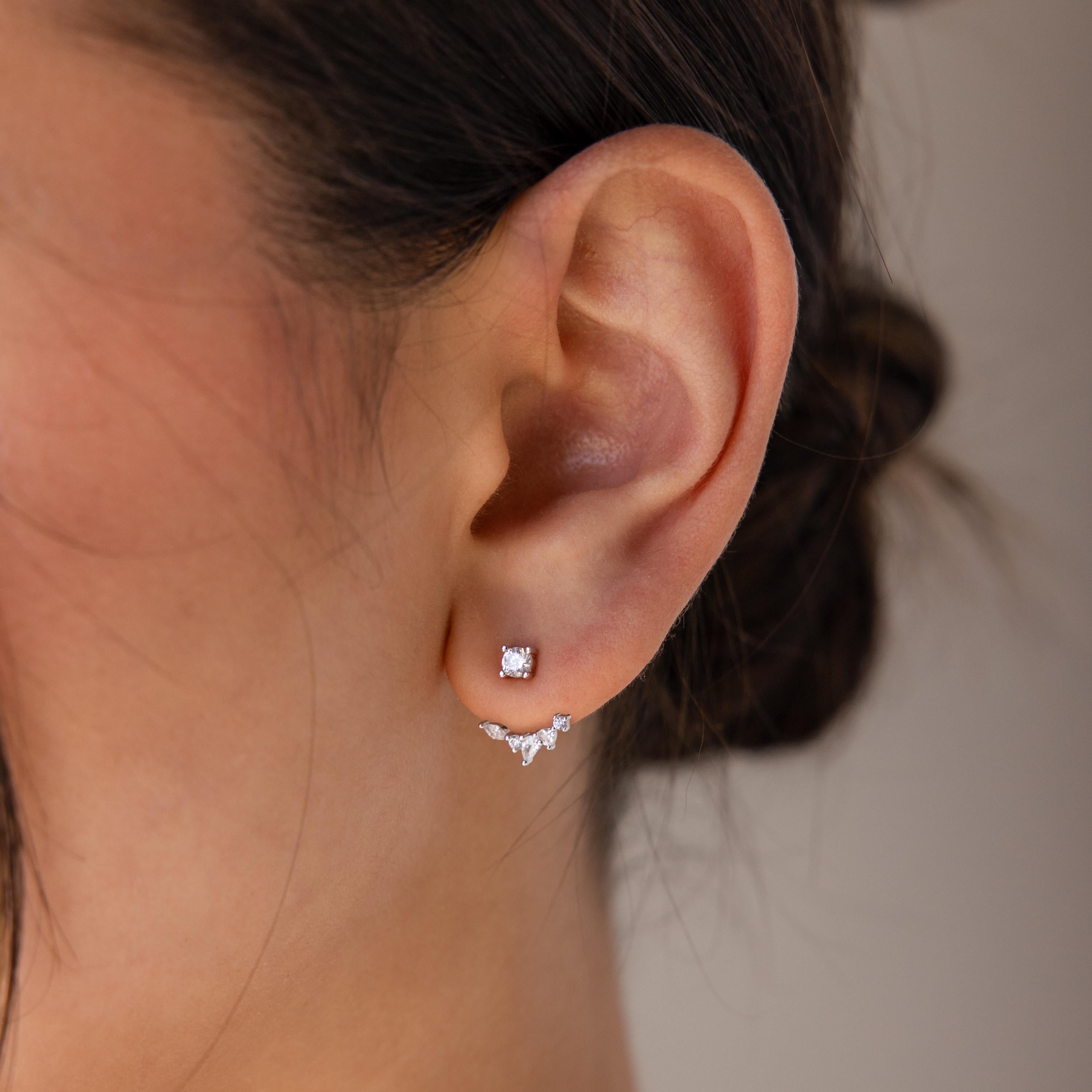 Close-up of a woman's ear adorned with Diamond Cluster Ear Jackets, featuring a square stud and a curved row of tiny gem studs in a chic front-back design.