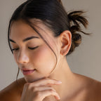 A woman with her hand on her chin elegantly showcases the Mini Diamond Sprinkle Huggies.