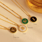 Four gold Gemstone Initial Disc Necklaces with letter charms are displayed on Tiger’s Eye, Pearl, Malachite, and Onyx—perfect for adding a unique touch of custom gemstone jewelry to your look.