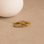 Chunky Pave Link Earrings with sparkling crystals, showcased on a beige textured surface next to a white round object for a bold yet elegant look.