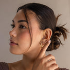 A woman with dark hair in a bun touches her Chunky Pave Link Earrings, gazing to the side against a neutral background.