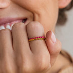 A person smiles while wearing the Engraved Birthstone Eternity Ring, a gold personalized ring with red stones and the engraved date 03.18.96, highlighting its unique and meaningful design.