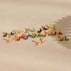 The Marquise Petal Birthstone Studs, gold earrings with colorful gemstones, are arranged neatly on a neutral surface with patterned shadows—ideal for lovers of personalized jewelry.