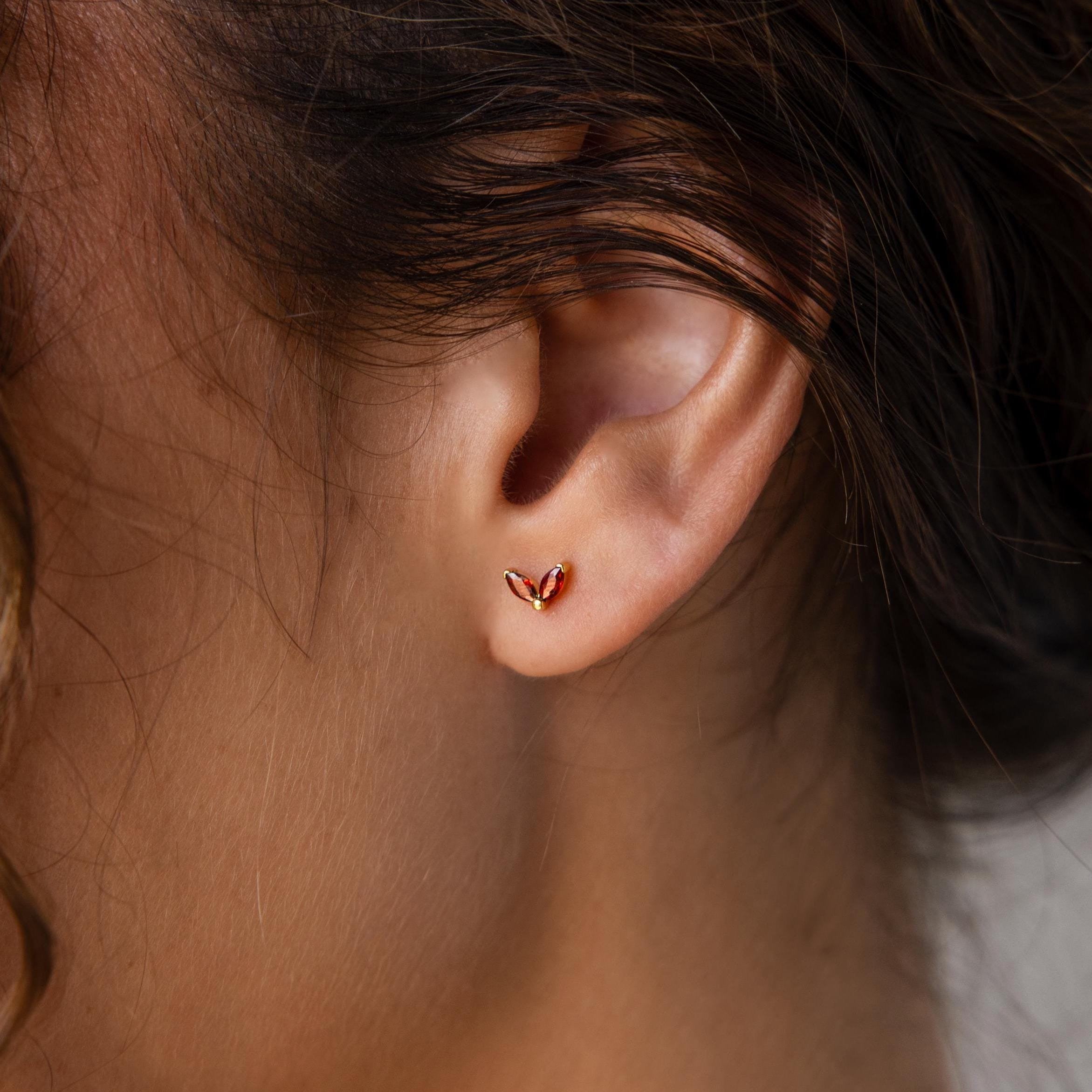 A close-up of a woman's ear adorned with Marquise Petal Birthstone Studs in Garnet (January), showcasing elegant personalized jewelry.