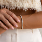 A woman wearing the Princess Diamond Tennis Bracelet, paired with a textured white top and matching white pants.