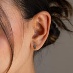 Close-up of a woman’s ear wearing Toi et Moi Birthstone Studs with two small gemstones; her hair is tied back, making these earrings an ideal personalized gift.