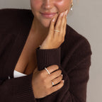 Woman wearing pearl jewelry and a brown sweater, featuring the Eternity Marquise Birthstone Ring—customizable with your birthstone—plus necklace, earrings, and manicured nails. A timeless gift idea for Christmas.
