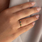 The Cluster Marquise Birthstone Ring features blue, green, and clear stones and is shown on a manicured hand resting on light fabric.