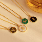 Four Gemstone Initial Disc Necklaces with gold round pendants labeled M, M, B, and E are displayed on beige fabric—ideal for adding a personalized touch to your style.