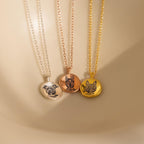 Three Pet Portrait Coin Necklaces in silver, rose gold, and gold rest on delicate chains against a beige background—a beautiful piece of pet memorial jewelry.